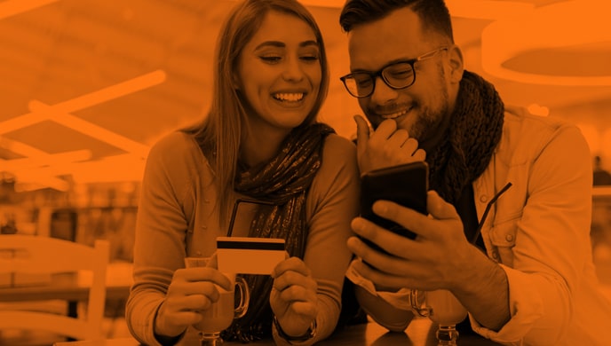 A couple holding a credit card and looking at a mobile phone